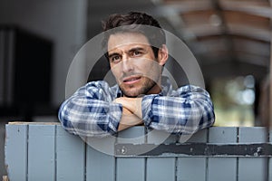 handsome farmer leaning in barn on tractor wheel photo