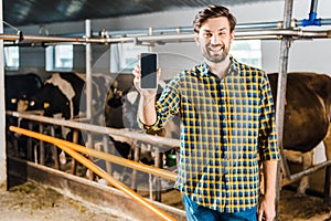 handsome farmer showing smartphone with blank screen