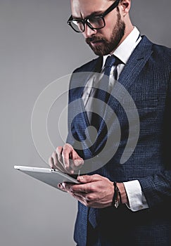Handsome fashion businessman dressed in elegant blue suit on gray background