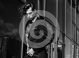 Handsome fashion male model dressed in elegant suit posing outdooe. Long haired Metrosexual. Black and white picture.