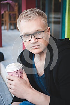 Handsome fashionable man in sunglasses drinking coffee