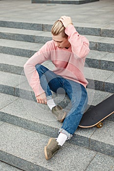 Handsome fashionable young man in a pink sweater and blue jeans