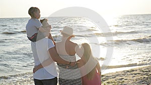 Handsome Father and Attractive Mother with Two Daughters Spending Time Together near the Sea During Sunset. Man Holding