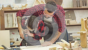 Handsome father and his teen son working with drill at workshop