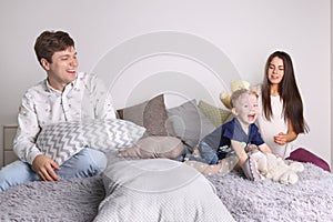 Handsome father, mother, little cute son play on bed