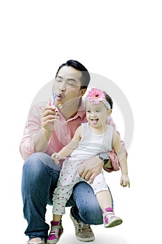Handsome father playing soap bubbles with daughter