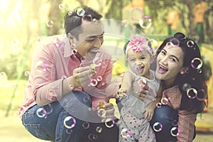 Handsome father playing soap bubbles with daughter