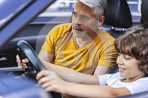 Handsome father teaching his son how to drive vehicle