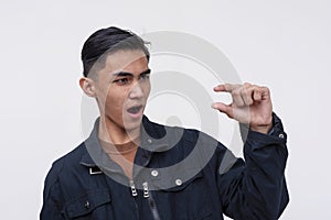 A handsome FIlipino guy mockingly describing something small or inadequate. Wearing a black jacket. Isolated on a white background
