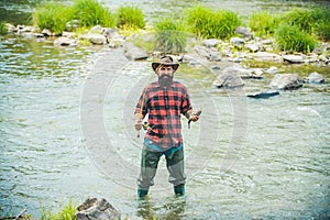 Handsome fisherman in a hat and a red checkered shirt. Fishing as holiday. Man relaxing nature background. It is not
