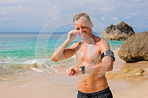 Handsome guy fixing his earbuds and getting ready for workout on the beach