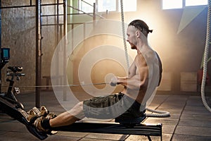 Handsome fit man during training on the simulators in the gym.