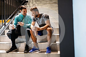 Handsome fit men friends talking, smiling after workout in gym