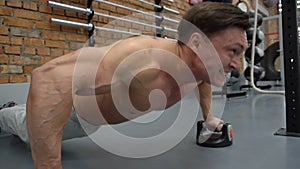 Handsome fitness man doing push ups in gym