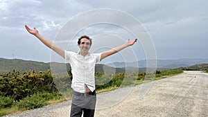 a handsome French or Spaniard man in a white shirt stands against the backdrop of mountains photo