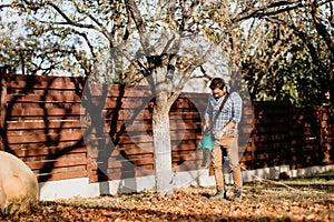 Handsome gardener working with leaf blower in garden