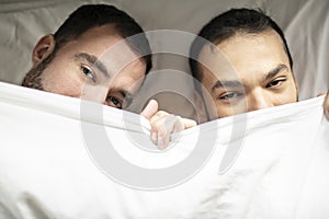 A Handsome gay men couple on bed together under the cover