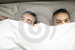 A Handsome gay men couple on bed together under the cover