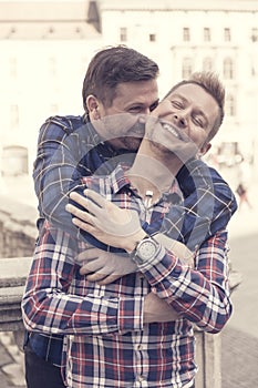 Handsome gay men couple hugging each other in the city