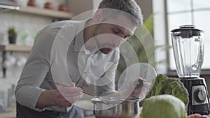 Handsome good-looking man in the shirt cooking soup in the kitchen. Concept of healthy food, home cooking. The guy