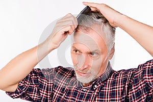 Handsome gray aged man combing hair