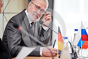 handsome gray haired elderly executive politician man sit at conference