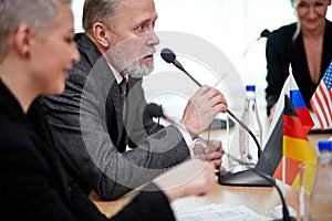 handsome gray haired elderly executive politician man sit at conference