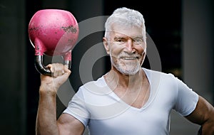 Handsome gray haired senior man with kettlebell weight in his hand. Sport and health care concept