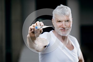 Handsome gray haired senior man vaccinated with a thermometer. Medicine and health care concept