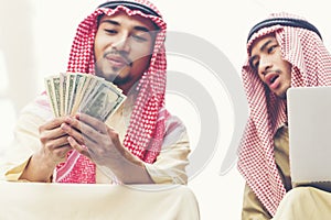 Handsome greedy arab man showing money on hands and counting money. Financial corruption Concept