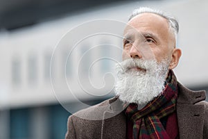 Handsome grey-haired senior man outdoors, looking at copy space
