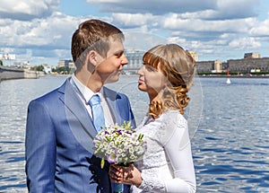 Handsome groom and beautiful bride on the river embankment