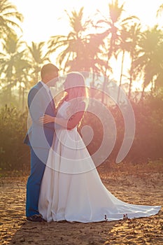 Handsome groom in a chic suit and a charming bride in a beautiful wedding dress look into each other`s eyes and smile at