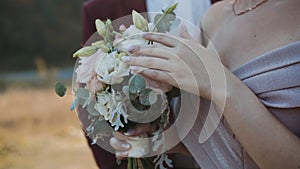 Handsome groom comes and kisses his bride on sunny nature