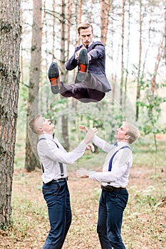 Handsome groom and groomsmen having fun and crazy in the forest while jumping on a wedding day.