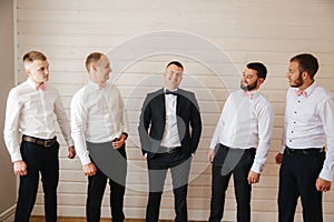 Handsome groom with his groomsman at home. Five man. Groom dressed in suit, gromsmen in white shirt. Funny guys on the
