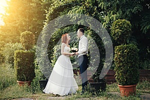 Handsome groom holds the bride& x27;s hand near green flower archway