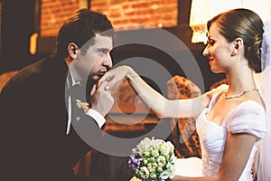 Handsome groom kisses bride's delicate hand