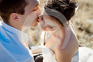 Handsome groom kisses his beautiful bride close up. Top view