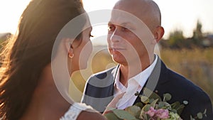 Handsome groom looking at pretty bride at romantic photoshoot after wedding ceremony. Happy couple in love tenderly