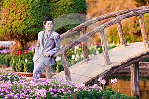 Handsome Groom Stand and Leaning at Wood Bridge in Park