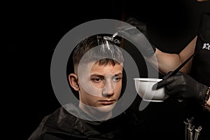 Handsome guy in barbershop. Young man with new haircut. Professional hairstyle. Model and trendy hairdressed. Barber is coloring