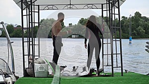 Handsome guy and beautiful girl are getting ready to swim on the wake