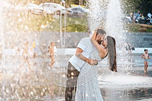 Handsome guy and beautiful girls kissing on the background of a fountain