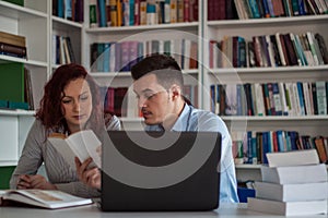 Handsome guy and beautiful redhead girl studying in the library