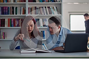 Handsome guy and beautiful redhead girl studying in the library