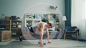 Handsome guy doing stretching exercises at home relaxing tense leg muscles