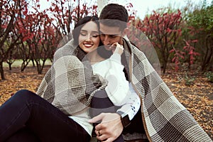 Guy with a girl sit in an embrace covering his shoulders with a photo