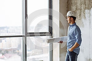 Handsome guy in hardhat putting his hand on the pocket and looking at the window