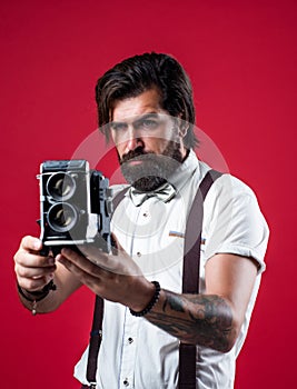 handsome guy hipster with moustache and beard making photo on vintage camera, photographing